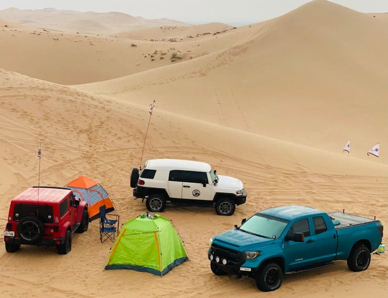 4x4 vehicles and tents set up among sand dunes