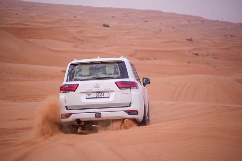 Toyota Land Cruiser driving through sand dunes