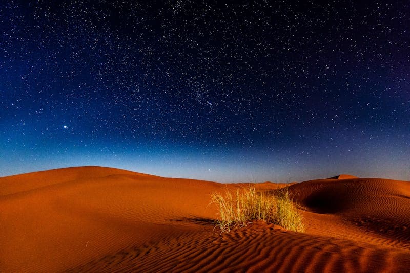 Starry night sky over desert sand dunes