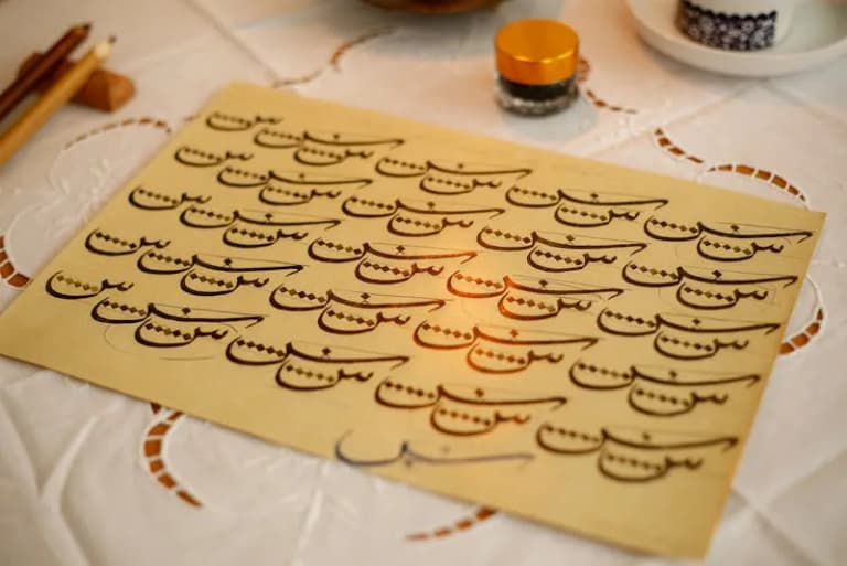 Close-up of Arabic calligraphy on paper with warm golden tones