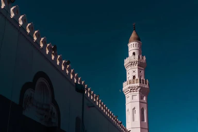 Quba Mosque minaret against a vivid blue sky in Medina