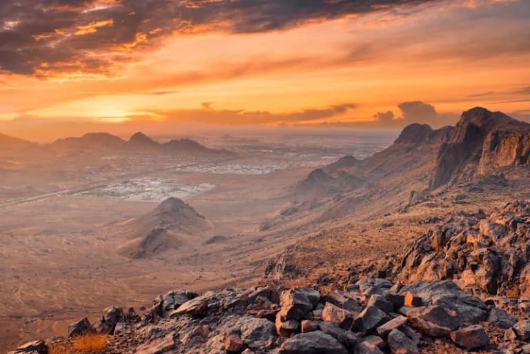 Rocky desert landscape near Medina at sunset with mountains in the distance