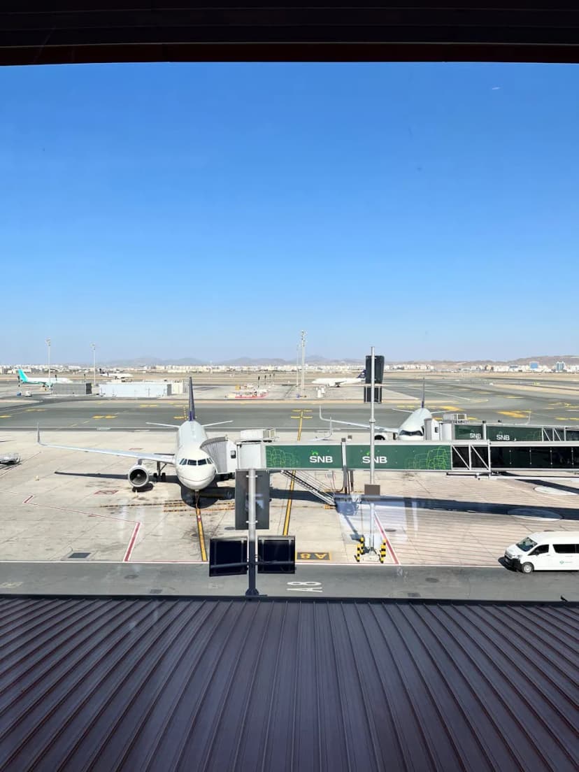 Airplane at terminal gate in Jeddah Airport under clear Saudi sky
